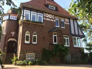 Pilgerherberge Altes Pfarrhaus Historisches Pfarrhaus aus Backstein mit Erker, Türmchen und blumengeschmückten Rundbogenfenstern.