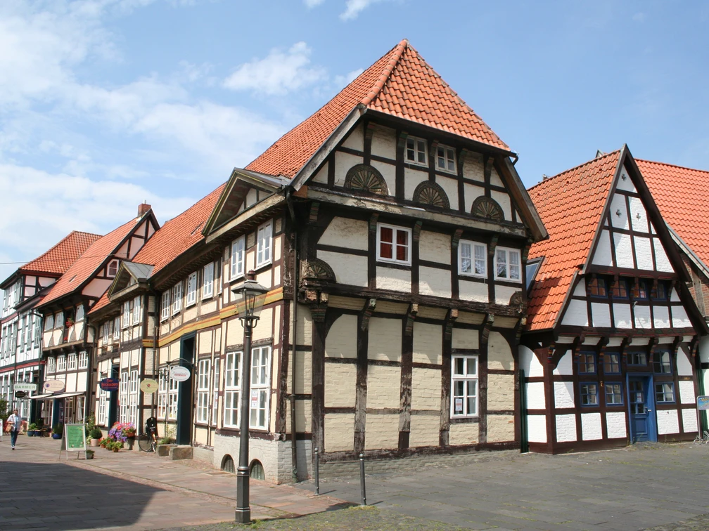 Altstadt Nienburg Fachwerkhäuser in Nienburg mit roten Ziegeldächern vor blauem Himmel und Kopfsteinpflasterweg.