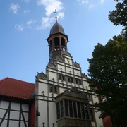 Historisches Gebäude in Nienburg mit markantem Turm und verziertem Fachwerk im Vordergrund.