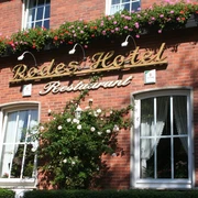 Rotes Backsteingebäude mit Blumen geschmückt, darunter der Schriftzug "Rodes Hotel Restaurant".