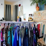Kleiderei Innenansicht einer Boutique mit bunter Kleidung auf Kleiderständern und dekorativen Pflanzen.Interior view of a boutique with colorful clothes on clothes racks and decorative plants.