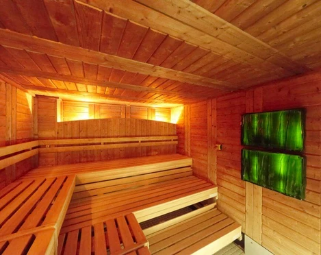 Agrippa bath Holzverkleidete Sauna mit zwei grünen Leuchten, warm erleuchtet, gemütlich und einladend.Wood-clad sauna with two green lights, warmly lit, cozy and inviting.