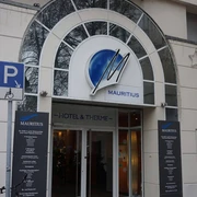 Mauritius Hotel and Spa Eingang zu Mauritius Hotel & Therme mit überdachtem Bogen und markantem blauen Logo.Entrance to Mauritius Hotel & Therme with covered arch and striking blue logo.