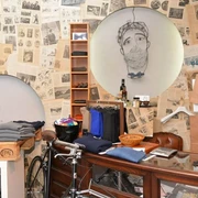 Greenwich Man Time  Ein stilvoll eingerichteter Laden mit Vintage-Charme, dekoriert mit alten Zeitungen. Im Fokus stehen elegante Männerkleidung, Accessoires und ein Fahrrad. Ein gezeichnetes Porträt an der Wand. Modern und traditionell vereint.A stylishly furnished store with vintage charm, decorated with old newspapers. The focus is on elegant men's clothing, accessories and a bicycle. A painted portrait on the wall. Modern and traditional combined.