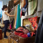 Vintage Emde In einem Vintage-Laden stöbert eine Person konzentriert durch bunte Kleidungsstücke und Accessoires.In a vintage store, a person is browsing through colorful clothing and accessories.