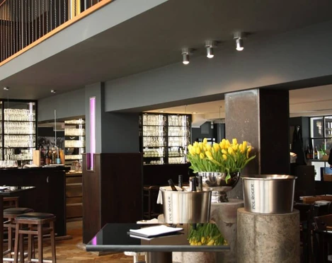Henne Weinbar Schlicht und elegant eingerichtetes Restaurant mit grauen Wänden und dunklen Möbeln.A simple and elegantly furnished restaurant with gray walls and dark furniture.