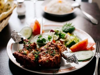 Ginti Nahaufnahme von einem Teller mit gebackenen Hähnchenschenkel und Salat.Close-up of a plate of baked chicken legs and salad.