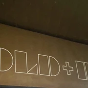 GOLD + BETON Das Bild zeigt eine Wand mit dem Schriftzug "GOLD + BETON" in weiß auf einem gold-braunen Hintergrund.Signboard displaying 'GOLD + BETON' in bold white letters, set against a dark wooden backdrop.