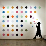 30works Galerie In einem weißen Raum ist eine Installation zu sehen, die aus einer Wand mit bunten Punkten besteht. Daneben die Silhouette eines Kindes, das Blasen pustet, und eine goldene Hirschkopfskulptur.In a white room, there is an installation featuring a wall covered in colorful dots. Next to it is the silhouette of a child blowing bubbles, and a golden deer head sculpture.