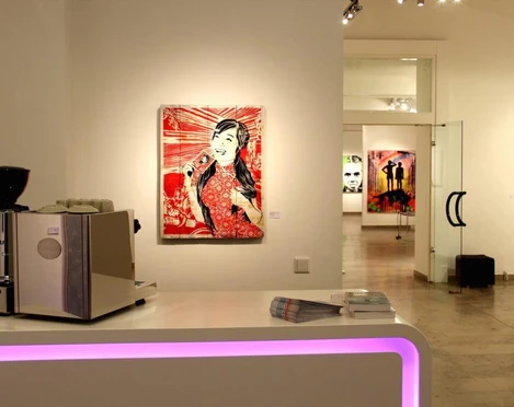 30work Galerie Innenansicht der 30works Galerie in Köln: Kunstwerke von mittenimwald und EMESS an den Wänden auf weißem Hintergrund, zentral ein Kunstwerk in Rottönen, Kontraste mit schlichter Möblierung.Interior view of the 30works gallery in Cologne: artworks by mittenimwald and EMESS displayed on white walls, centrally featuring a piece dominated by shades of red, contrasted by minimalist furnishings.