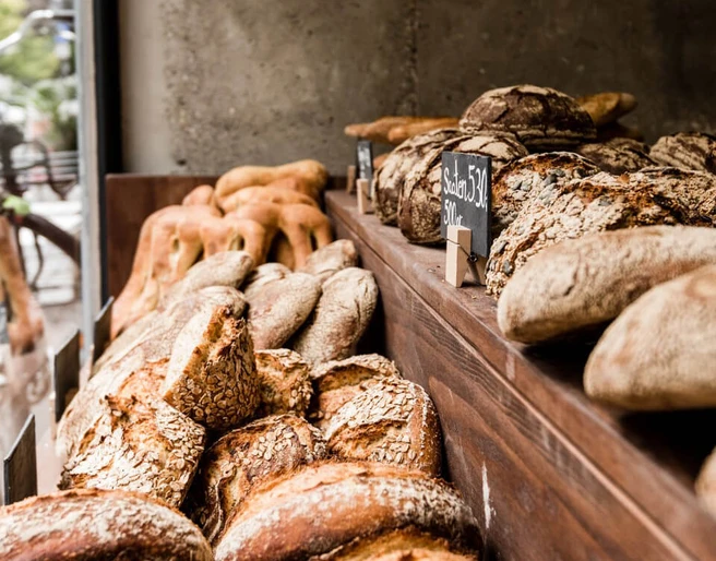 prôt Eine rustikale Brotauslage zeigt eine Vielfalt frischer Brote, darunter Krustenbrote und Körnerstangen.A rustic bread display showcases a variety of fresh breads, including crusty loaves and grain sticks.