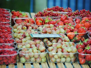 Farmers’ market in Deutz Frisches Obst, darunter Erdbeeren, Himbeeren und Stachelbeeren, auf einem Holztisch präsentiert.Fresh fruit, including strawberries, raspberries and gooseberries, presented on a wooden table.