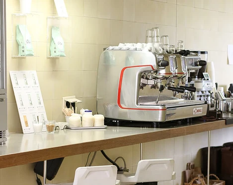 VAN DYCK Espressobar Eine moderne Kaffeerösterei mit silberner Espressomaschine, Barhockern und gemütlicher Atmosphäre.A modern coffee roastery featuring a silver espresso machine, bar stools, and a cozy atmosphere.