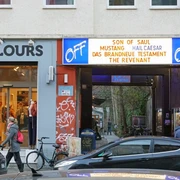 OFF Broadway Eingang des OFF-Broadway-Kinos in Köln, mit Passanten und parkenden Autos.Entrance to the OFF-Broadway cinema in Cologne, with passers-by and parked cars.