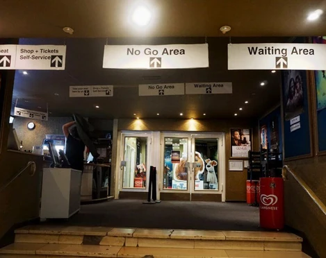 Metropolis Eingangsbereich eines Kinos mit beleuchteten Schildern, die die verschiedenen Bereiche kennzeichnen.Entrance area of a movie theater with illuminated signs indicating the different areas.