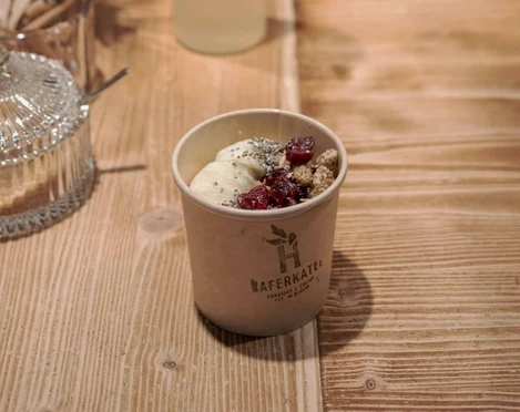 Haferkater Ein Haferbrei mit Früchten und Zimt zum Mitnehmen in einem Pappbecher.A bowl of porridge with fruit and cinnamon to go, in a paper cup.