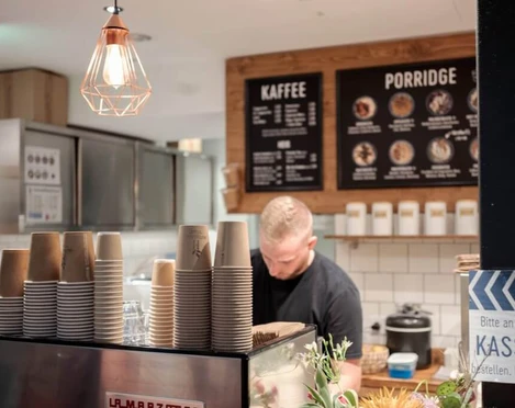 Haferkater Blick in das Bistro auf eine Espressomaschine und Kreidetafeln an der Wand.View of an espresso machine and chalk boards on the wall in the bistro.