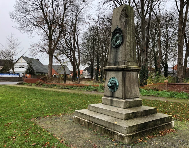 Herzog-Wilhelm Denkmal Thedinghausen Herzog-Wilhelm Denkmal in einem grünen Park, umgeben von herbstlichen Bäumen und Gebäuden im Hintergrund.