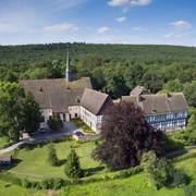 Kloster Falkenhagen Luftaufnahme des Klosters Falkenhagen inmitten grüner Wälder unter einem klaren blauen Himmel.
