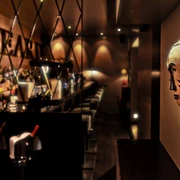 Samuel's Shep Eine stilvolle Bar mit einer kunstvollen Maske an der Wand. Die Bar ist elegant beleuchtet und lädt zu einem entspannten Abend ein.A stylish bar featuring an artistic mask on the wall. Elegantly illuminated, the bar invites guests for a relaxed evening.