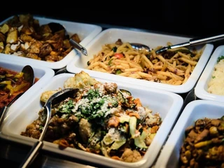 Sattgrün Eine Auswahl an Speisen in Buffet-Schalen, darunter Pasta, Kartoffeln und Gemüsegerichte.A selection of dishes presented in buffet trays, including pasta, potatoes, and vegetable options.