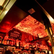 Frieda Bar Bar in rotem Licht beleuchtet mit Aufklebern an der Decke. Bar in red light illuminated with stickers on the ceiling.