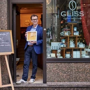 Michael Glisss Ein Mann steht mit einer Auszeichnung vor dem Café „GLISS“A man stands with an award in front of the "GLISS" café