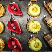 Törtchen Törtchen  Eine Auswahl an kunstvoll dekorierten Törtchen auf einer Schieferplatte, jedes einzigartig verziert.An assortment of artistically decorated tartlets presented on a slate platter, each uniquely garnished.