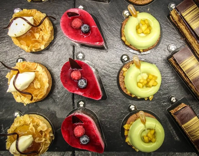 Törtchen Törtchen  Eine Auswahl an kunstvoll dekorierten Törtchen auf einer Schieferplatte, jedes einzigartig verziert.An assortment of artistically decorated tartlets presented on a slate platter, each uniquely garnished.