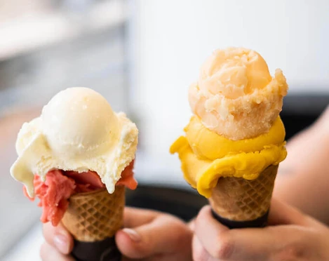 ice cream parlor Keiserlich Nahaufnahme, eine Person hält zwei Waffelhörnchen mit jeweils zwei Kugel Eis in die Kamera. Close-up of a person holding two waffle cones, each with two scoops of ice cream, up to the camera.