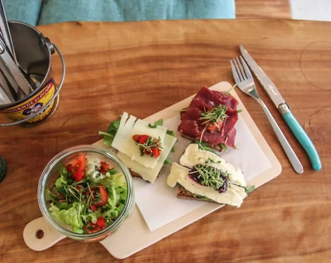 Cafe Geschnitten Brot Auf einem Holzbrettchen liegen drei schön belegte Brote und ein kleiner Salat in einem Glas Schüsselchen. Three tasty sandwiches and a small salad in a glass bowl on a wooden board.