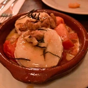 Tapeo and co Eine rustikale Tonschale gefüllt mit überbackenem Ziegenkäse, Tomaten, Walnüssen und Rosmarin.A rustic clay bowl filled with baked goat cheese, tomatoes, walnuts, and rosemary.