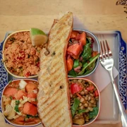 Veedel Vital Eine bunte Salat-Auswahl mit Quinoa, Linsen, Tomaten, Limette und getoastetem Brot auf einem blau verzierten Teller.A colorful salad assortment featuring quinoa, lentils, tomatoes, lime, and toasted bread, served on a blue decorated plate.