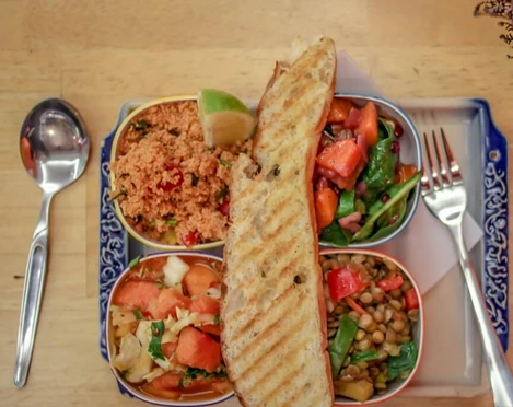 Veedel Vital Eine bunte Salat-Auswahl mit Quinoa, Linsen, Tomaten, Limette und getoastetem Brot auf einem blau verzierten Teller.A colorful salad assortment featuring quinoa, lentils, tomatoes, lime, and toasted bread, served on a blue decorated plate.