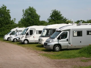 Wohnmobilstellplatz am Schloss Erbhof Thedinghausen Wohnmobile parken auf einem grasbewachsenen Stellplatz neben einem Schloss im Grünen.