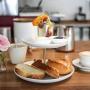 Cafe dein und mein Ein köstliches Frühstücksset mit frisch gebackenen Brötchen, Butter, Marmelade, Obst und Kaffee.A delicious breakfast set with freshly baked rolls, butter, jam, fruit and coffee.
