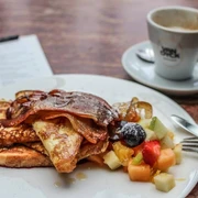 Cafe Sehnsucht French Toast mit frischem Obst und Speck, dazu eine Tasse KaffeeFrench Toast with fresh fruitand bacon, served with a cup of coffee