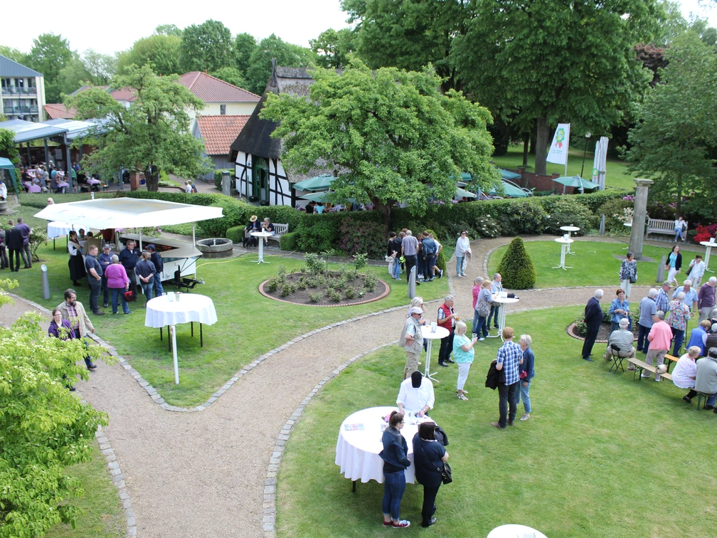Nienburger Spargelfest Menschen genießen ein Spargelfest im Freien mit Ständen und Tischen, umgeben von grüner Natur.