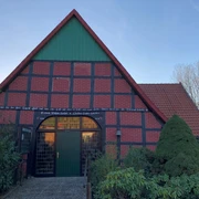 Katholische Kirche Windheim Ein traditionelles Fachwerkhaus mit rotem Ziegeldach und grünem Gartentor, umgeben von Bäumen.