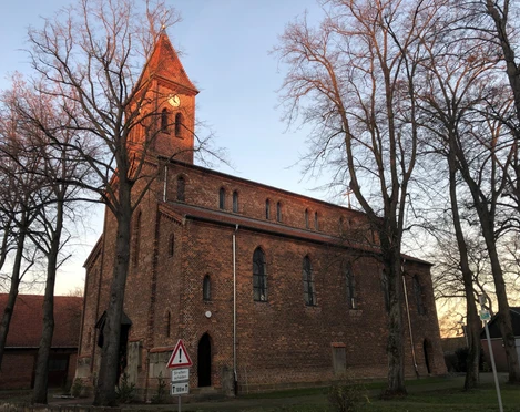 Kirche Friedewalde Backsteinkirche aus dem 19. Jahrhundert mit hohem Turm, umgeben von kahlen Winterbäumen.