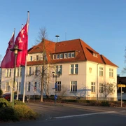 Rathaus Lahde Ein historisches Gebäude im späten Nachmittagslicht, mit rosa Fahnen rechts davor.
