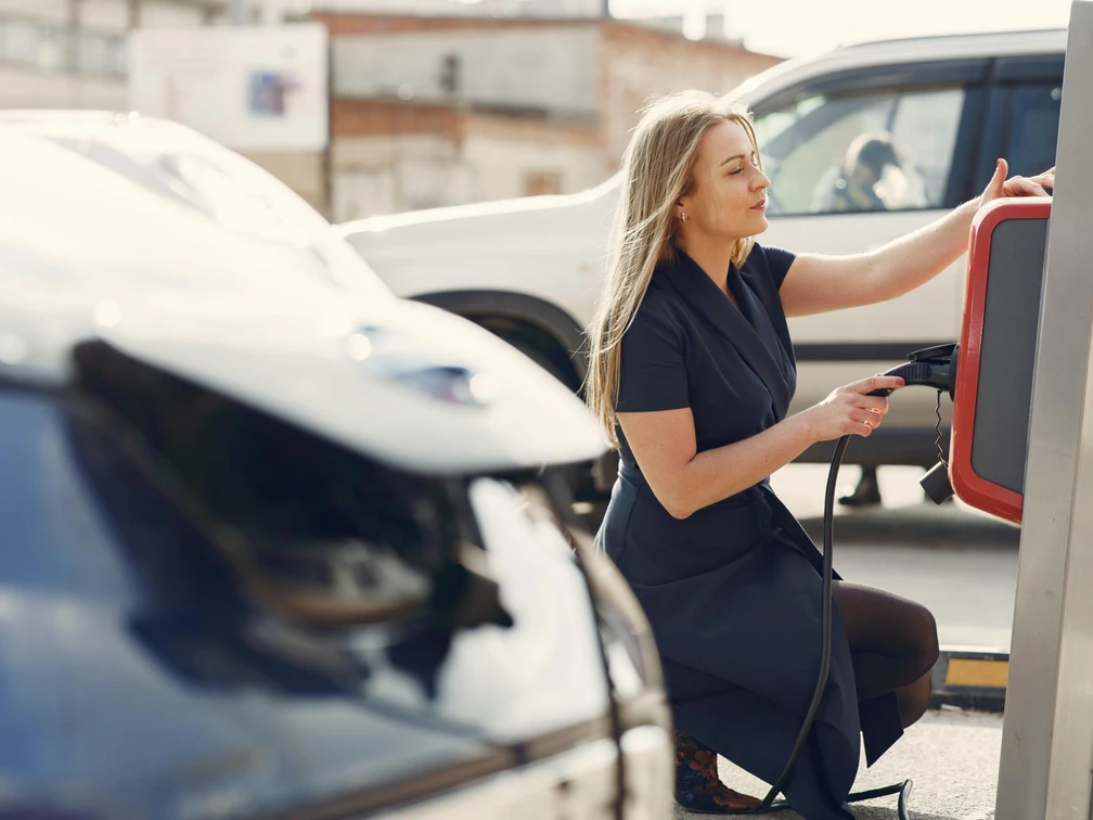 beispiel-e-mobilitaet_pexels-gustavo-fring-.JPG Eine Frau in schickem Kleid nutzt eine Ladesäule für Elektrofahrzeuge auf einem Parkplatz.