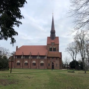 St. Michaelis-Kirche Heemsen Backsteinkirche St. Michaelis in Heemsen, umgeben von Bäumen auf einer großen, offenen Grünfläche.