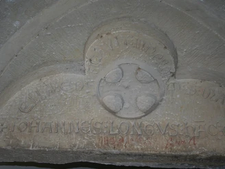 Steinrelief im Kloster Loccum mit lateinischer Inschrift und Kreuzsymbol, verwittertes Erscheinungsbild.