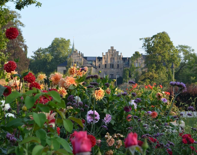 Schloss Ippenburg Tuin met rozen bij het Kasteel Ippenburg in Bad Essen in het Osnabrücker LandHistorisches Schloss im Hintergrund, Vordergrund mit bunten Blumen im Park.