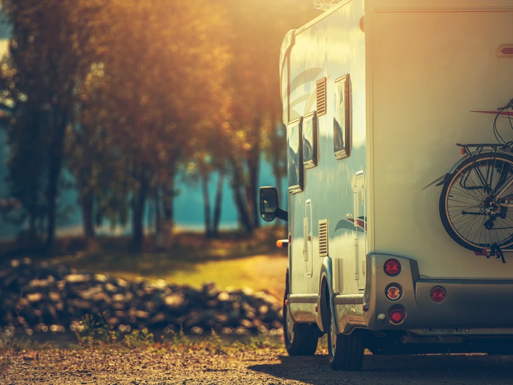 AdobeStock_Camping 3.jpeg Autumn RV Camping. Modern Camper Van During Late Sunny Fall Afternoon. Scenic RV Park.