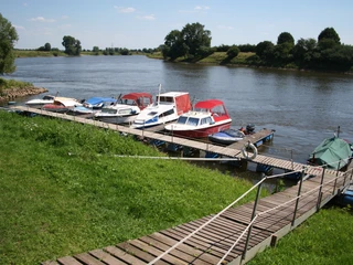 Bootsanleger Langwedel-Drosselhof Bootsanleger am Fluss mit mehreren Booten festgemacht, umgeben von grüner Wiese und Bäumen.