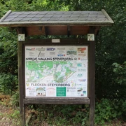 Nordic Walking Steyerberg Eine Informationstafel mit Übersichtsplan und Sponsorlogos steht in einem grünen Waldgebiet.