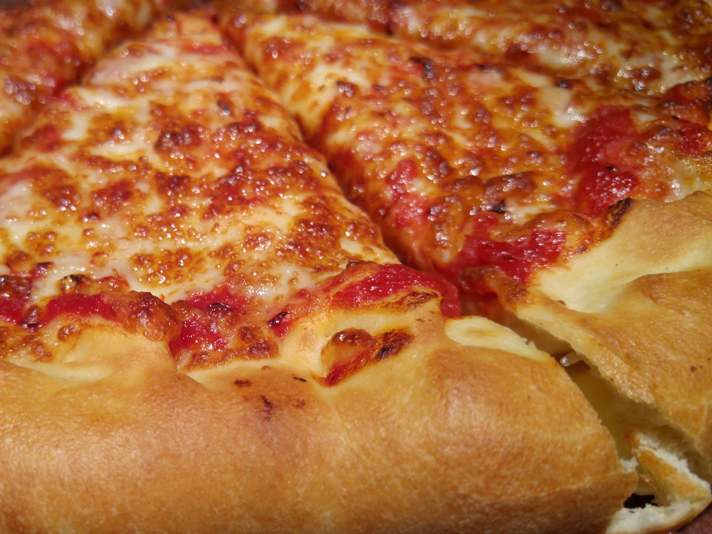 Eine perfekte, goldbraun gebackene Pizza mit geschmolzenem Käse und saftigem Tomatenbelag.