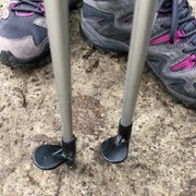 Nordic Walking Wanderschuhe und Nordic Walking-Stöcke auf einem Betonweg, bereit für Outdoor-Aktivitäten.